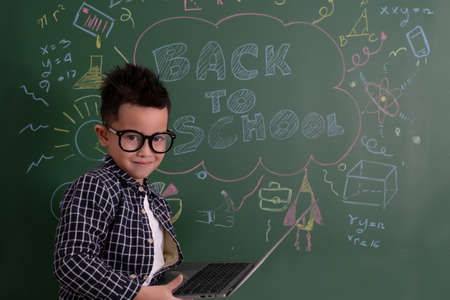 Asian little boy standing on the blackboard.