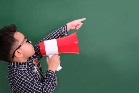 little boy in casual dress having fun with megaphone on blackboard.の写真素材