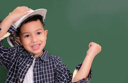 Asian little boy wear white engineer hat on blackboard.の写真素材