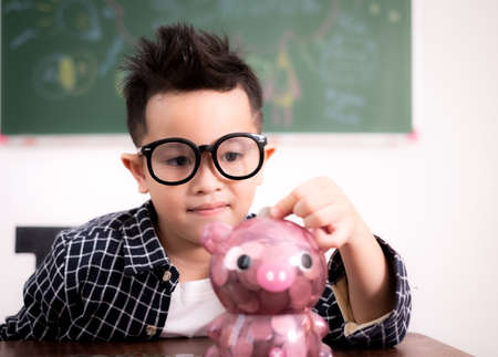 Asian little boy wear white engineer hat on blackboard.の写真素材