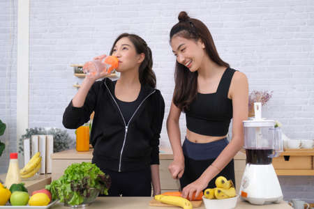 Young couple women with sports clothing enjoy to make saladの写真素材