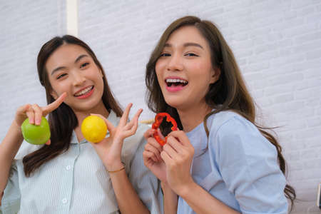 Young Asian couple women enjoy to cooking salad at home.の写真素材