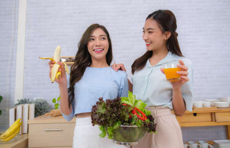Young Asian couple women enjoy to cooking salad at home.の写真素材
