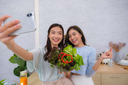 Young Asian couple women enjoy to cooking salad at home.の写真素材