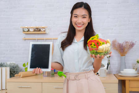 Young Asian couple women enjoy to cooking salad at home.