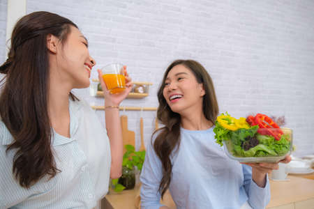 Young Asian couple women enjoy to cooking salad at home.の写真素材