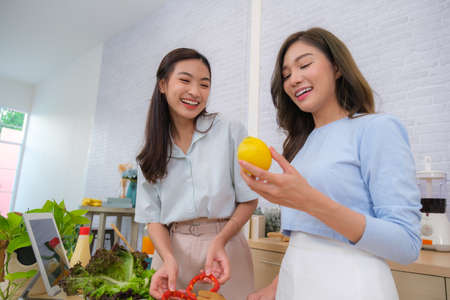 Young Asian couple relaxing in bed reading the book and using laptop to shop onlineの写真素材