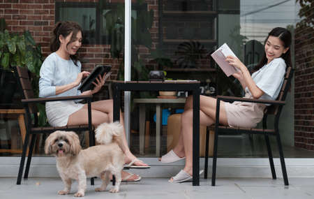 Young Asian couple relaxing in bed reading the book and using laptop to shop onlineの写真素材