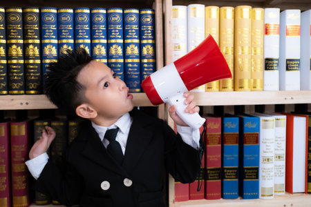 Little boy in suits holding megaphone in library.の写真素材