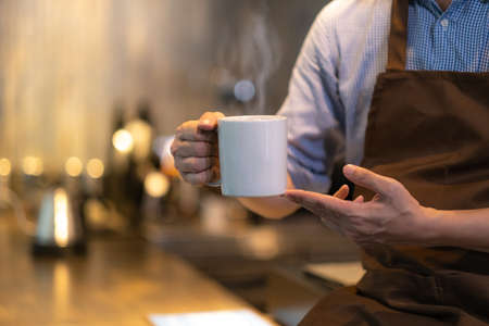 Hand's of barista hold coffee cup in restaurant.の写真素材
