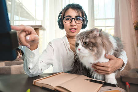 Young Asian woman working from home with her cat at home.
