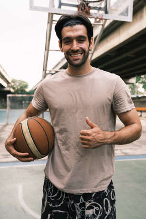 Young causian basketball player shooting ball on street court.の写真素材