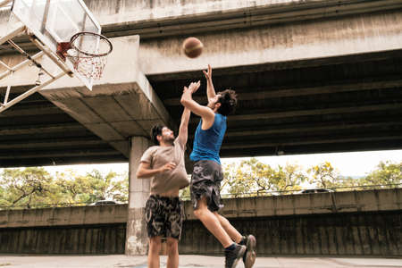 Two caucasian men pratice baskegball in court at urban street.の写真素材