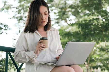 Young Asian woman working with notebook in park