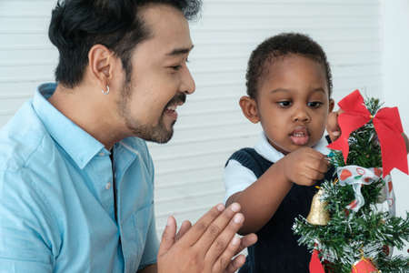 Daddy and son enjoy using times to decrorate christmas tree and take a selfie with mobile at home.の写真素材