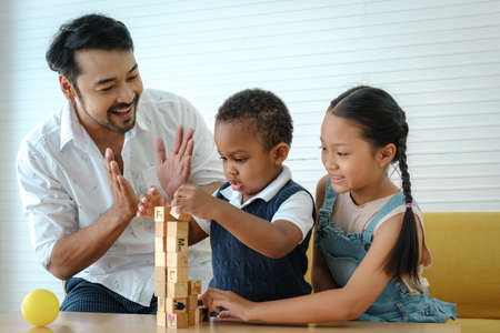 Asian family. Father with son and daughter spending times to play wooden toys together at home.の写真素材