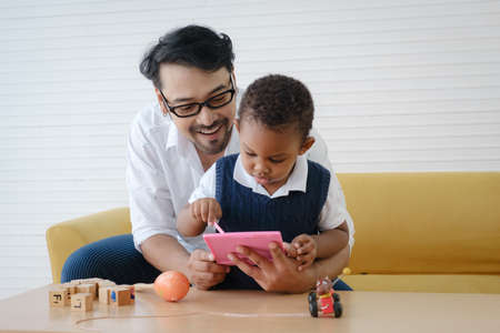 Asian Father spending times with his son to playing toys together.