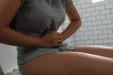 Young woman sitting on toilet and stomach ache.