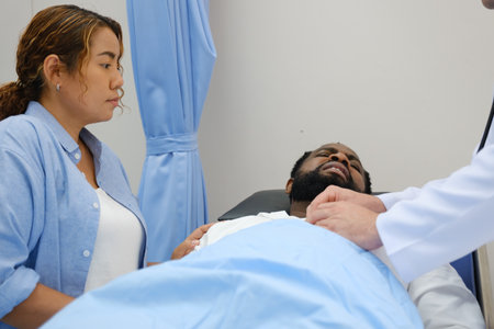 Doctors examines a black patient who has had an accident with a broken leg accompanied by his wife...