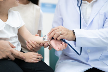 The doctor held the young patient's hand, and the mother smiled and encouraged her.の写真素材