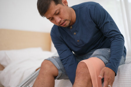 Asian man using Crutches Because he is infury at knee and he first aid with bandage.の写真素材