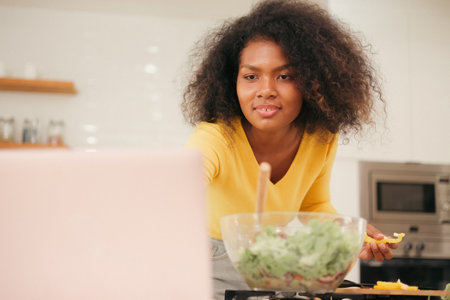 Multiracial young woman cooking salad at home.の写真素材