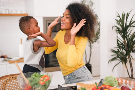 Multiracial mother cooking salad with her liitle boy at home.の写真素材