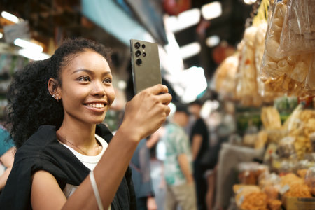 Asian woman enjoy travel in  downtown district and she taking a photo and using mobile live on social media and tasting streetfoods.の写真素材