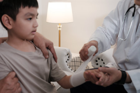 The doctor treats a wound on a boy's arm at homeの写真素材