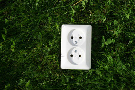An electrical cord connected to an electrical socket that generates power from green grass or other relevant natural sources of energyの写真素材