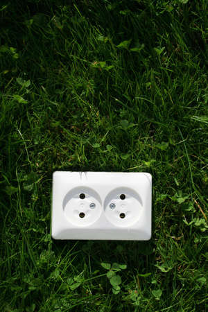 An electrical cord connected to an electrical socket that generates power from green grass or other...