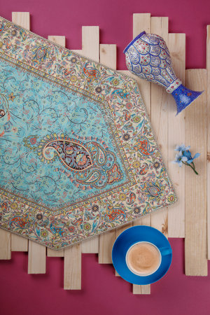 Top view of cup of coffee and oriental rug on wooden table
