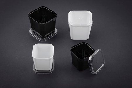 Black and white plastic container for food on black background . Disposable tableware