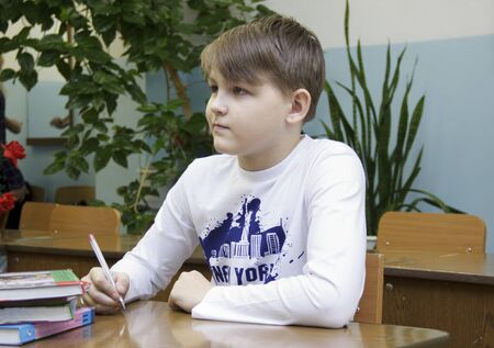 Russia, Krasnoyarsk region, Igarka, December 2015: back to school. the guy sits at his Desk and attentively listens to the teacherのeditorial素材