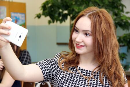 Russia, Krasnoyarsk region, Igarka, February 2016: back to school. student takes pictures of himself on the phone. selfie at schoolのeditorial素材