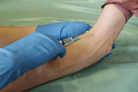 vaccination with a syringe. medical injection, needle in hand. a shot in the vein on his arm.