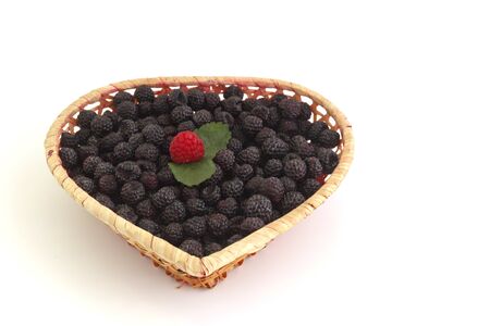 blackberries in a basket in the form of a heart on a white background.