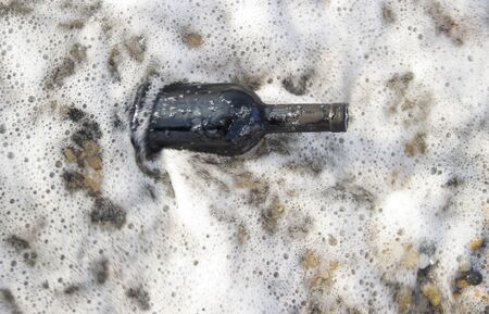 bottle of wine in the sea waves. Romantic day with glasses of red wine sitting on the beach of tropical island at the summer sunny day. Waves and sea on the background. Wedding concept...の写真素材