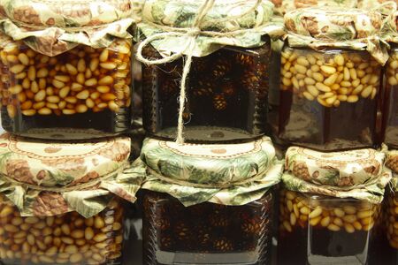 nuts filled with honey in glass jars are on wooden shelves at the food exhibition. Healthy food...の写真素材