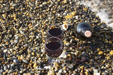 Romantic day with glasses of red wine, on the beach on a Sunny autumn day. Waves and sea in the background. The concept of the wedding.の写真素材