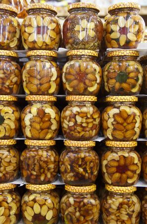 Glass jars filled with honey, nuts and fruit on the store counter.の写真素材