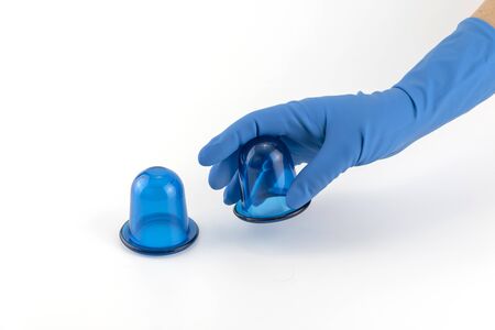 hand in medical glove holding blue anti-cellulite vacuum silicone body jars. massage and Wellness...