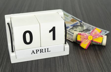 perpetual calendar with wooden cubes. the concept of celebrating the birthday of the dollar on April 01. dollar tied with a festive bow. American currency, paper currency notesの写真素材