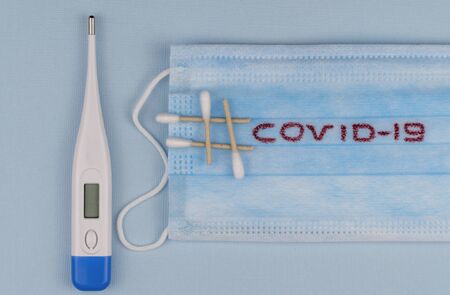 antiviral medical mask for protection against coronavirus. Surgical respiratory bandage face and electronic thermometeron on white background. prevention of the spread of virusの写真素材