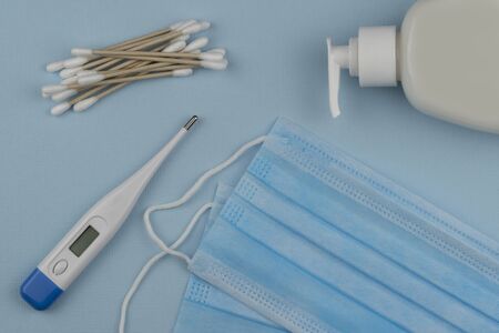 Coronavirus prevention surgical masks and hand sanitizer gel for hand hygiene spread protection. electronic thermometer for measuring body temperature. top viewの写真素材