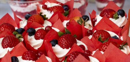 dessert with blueberries and strawberries in cups with cream. delicious berry background.