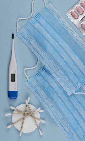 stop global epidemic of COVID-19. Coronavirus prevention surgical masks. Medical respiratory bandage face, electronic thermometer for measuring body temperature. top view. quarantine, stay at home.の写真素材