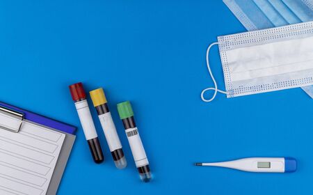 Flat lay composition with blood test tube and electronic thermometer on blue background. antiviral medical mask for protection against coronavirus COVID-19の写真素材