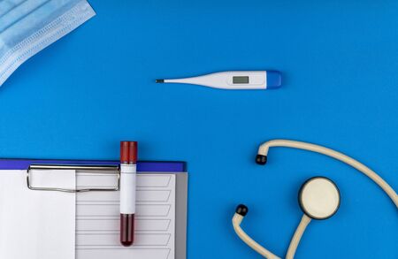 Flat lay composition with blood test tube and electronic thermometer on blue background. antiviral medical mask for protection against coronavirus COVID-19.の写真素材