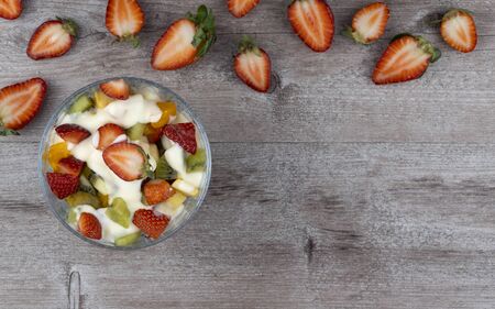 fruit salad in a glass plate and strawberry berries. flat layout, copy space. richest source of nutrients and vitamins. juicy and fresh berries, the concept of healthy and dietary food.の写真素材